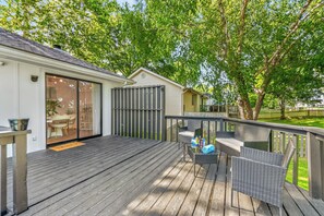 A wooden deck with outdoor furniture, a sliding glass door, and a fenced area.