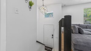 En modern inredning med en vit dörr, en geometrisk lampa och en inramad tavla på väggen.