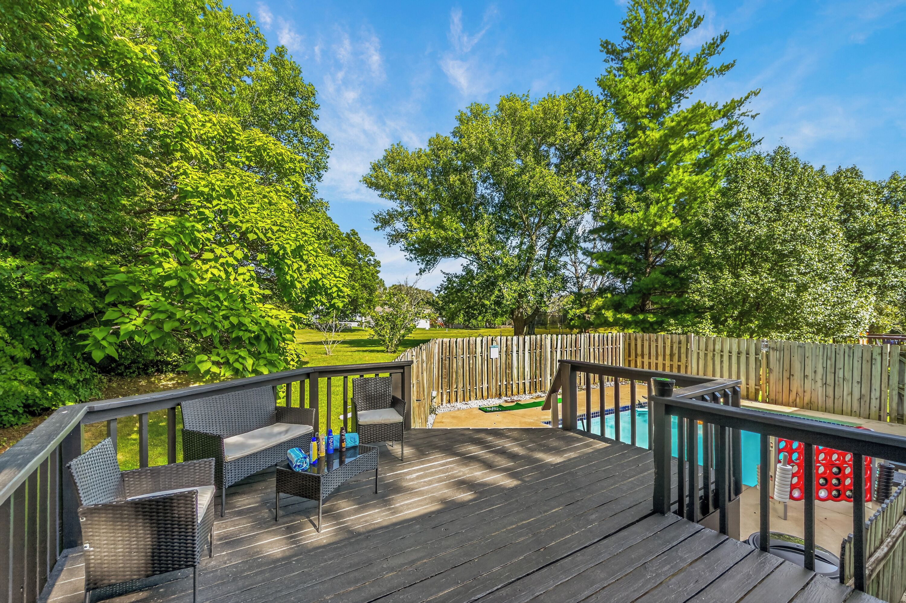 A wooden deck with outdoor furniture, a pool, and a wooden fence.