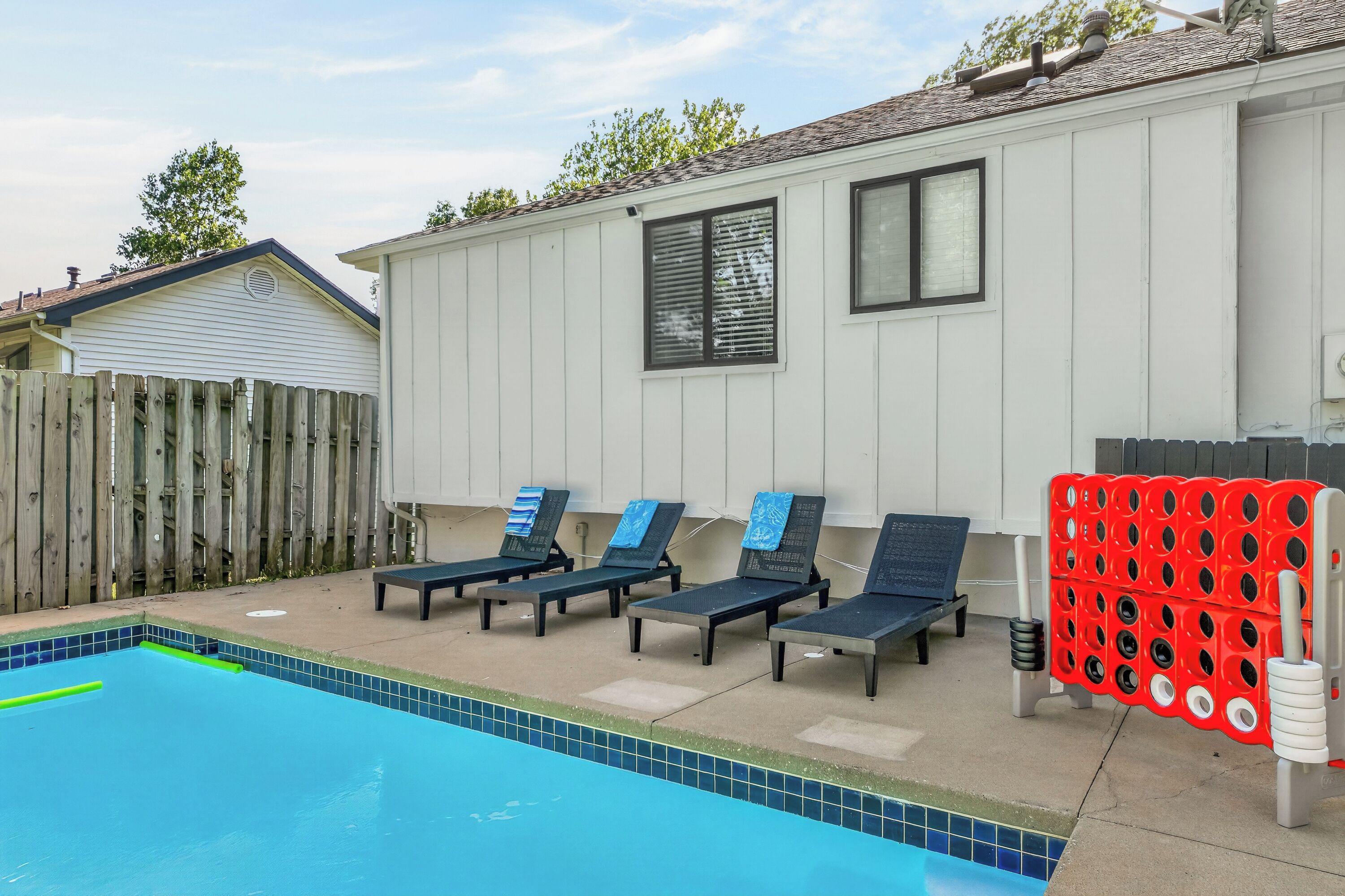 Un espace piscine avec des chaises longues et un porte-bouées rouge.