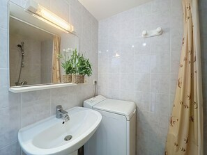Een badkamer met een wastafel, spiegel, douche en toilet.