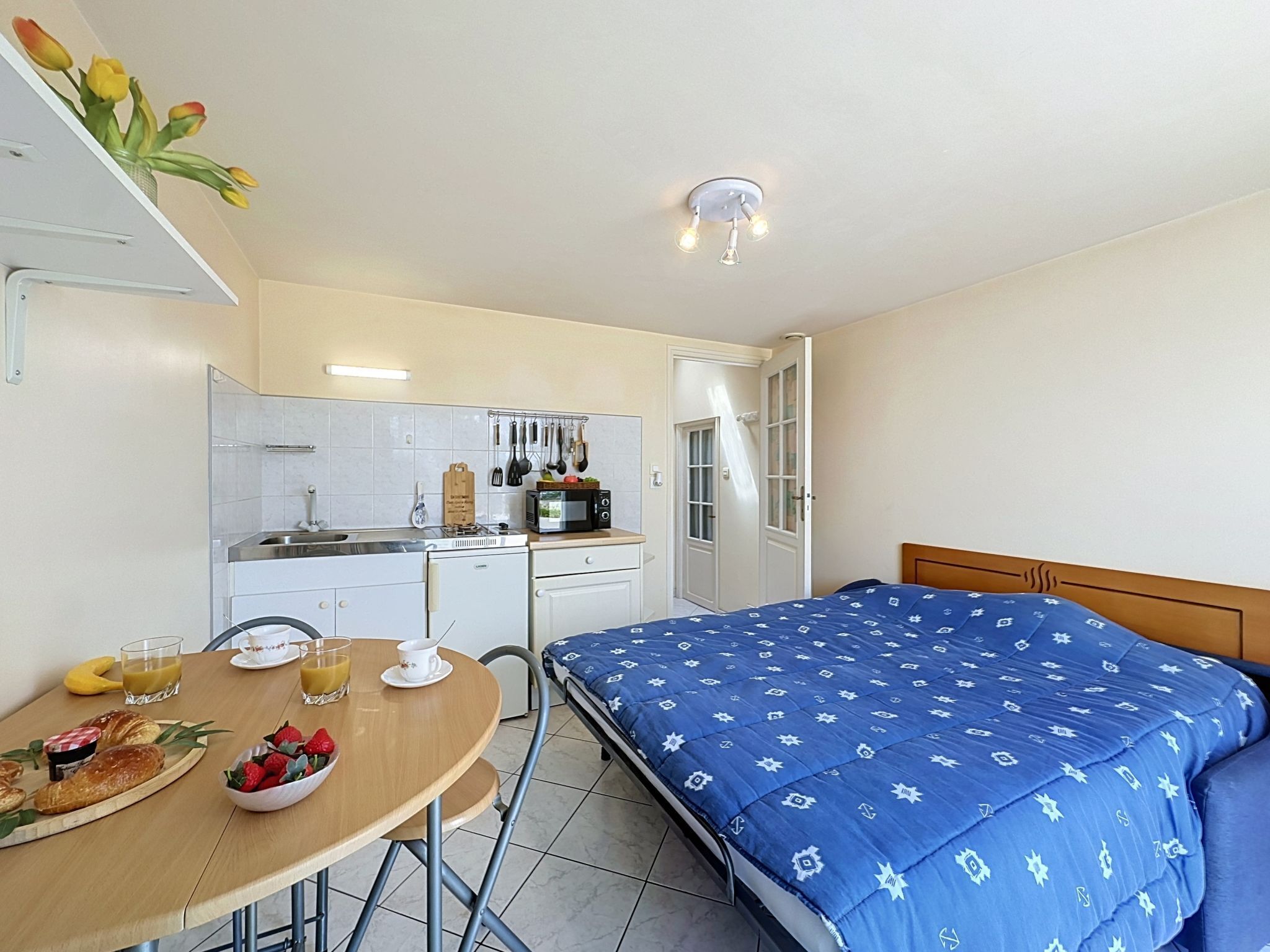 A compact room with a bed, a small kitchenette, and a dining area with breakfast.