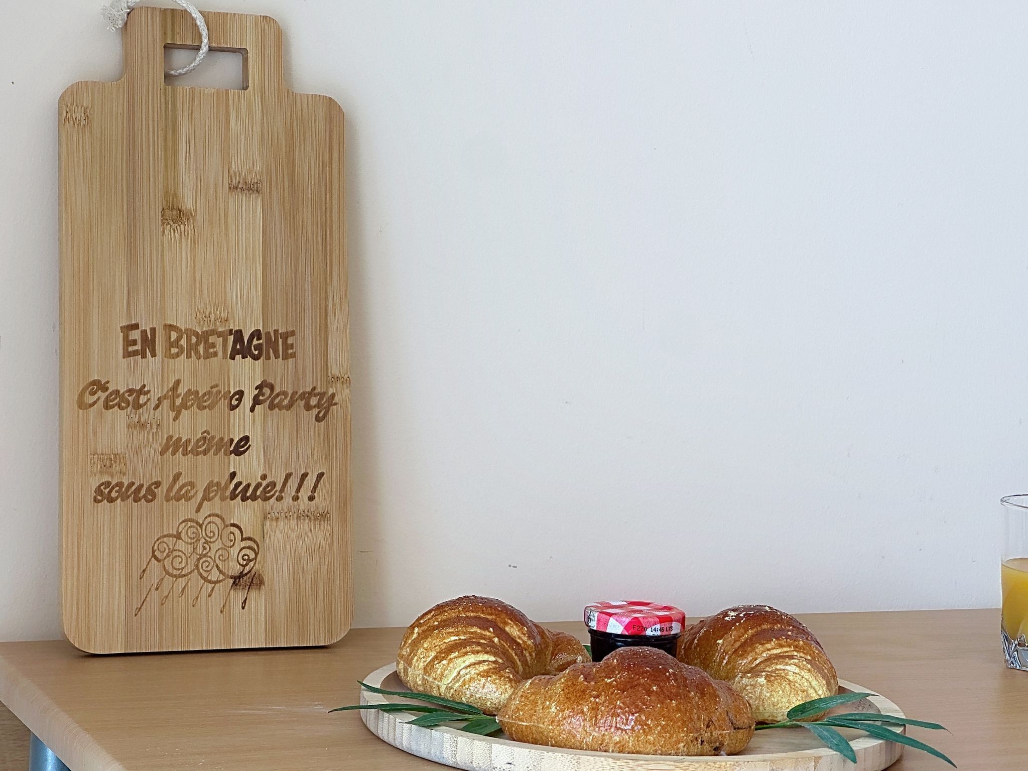 A wooden cutting board with text and a plate of croissants.