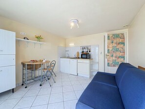 Una cucina compatta con angolo pranzo, divano e pavimento piastrellato.