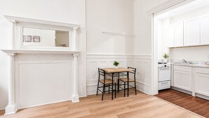 Uma cozinha com armários brancos, uma mesa de jantar de madeira com cadeiras e uma pequena planta sobre a mesa.