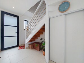 A staircase with a wooden handrail and white walls, leading to a landing with a closed door and a clock on the wall. - Ty Ar Mor by Interhome (Guilvinec)