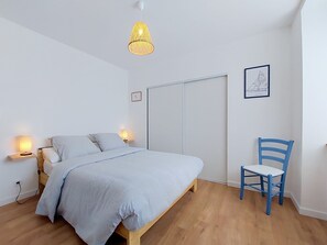 A bedroom with a bed, bedside lamps, a chair, a wardrobe, and a hanging light fixture. - Ty Ar Mor by Interhome (Guilvinec)