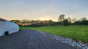 En gräsklädd åker med en grusgång och en byggnad med ett välvt tak.