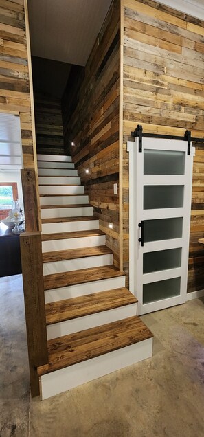 Una escalera con peldaños de madera y una puerta blanca con paneles de vidrio esmerilado.