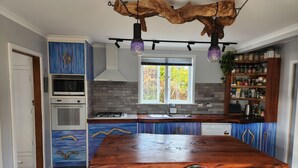 Una cocina moderna con una isla central, electrodomésticos integrados y una lámpara rústica en el techo.