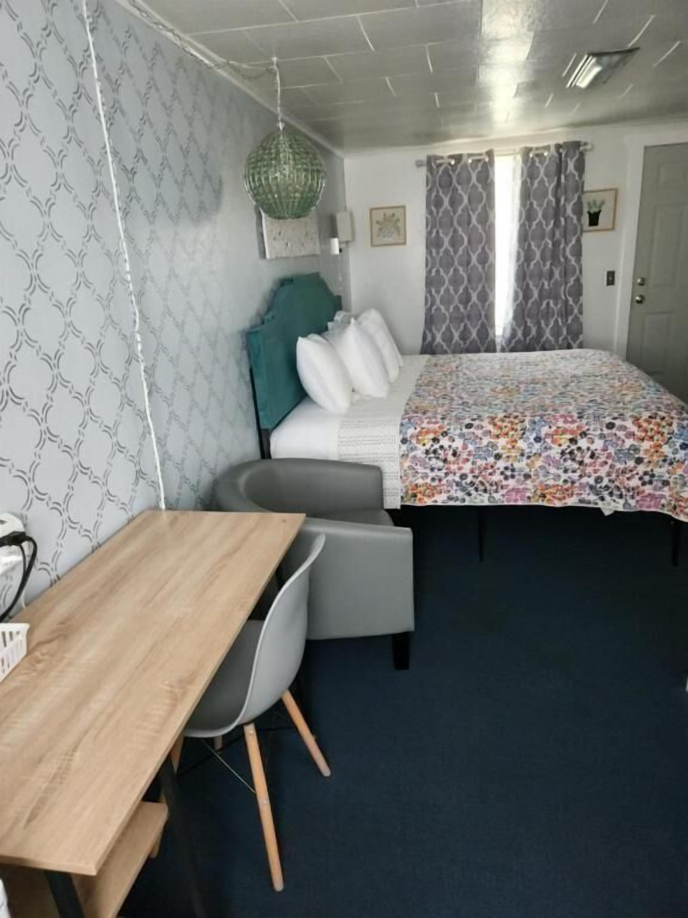 A bedroom with a bed, a desk, and a chair.