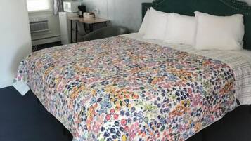 A bedroom with a floral bedspread, a green headboard, and a decorative wall piece.