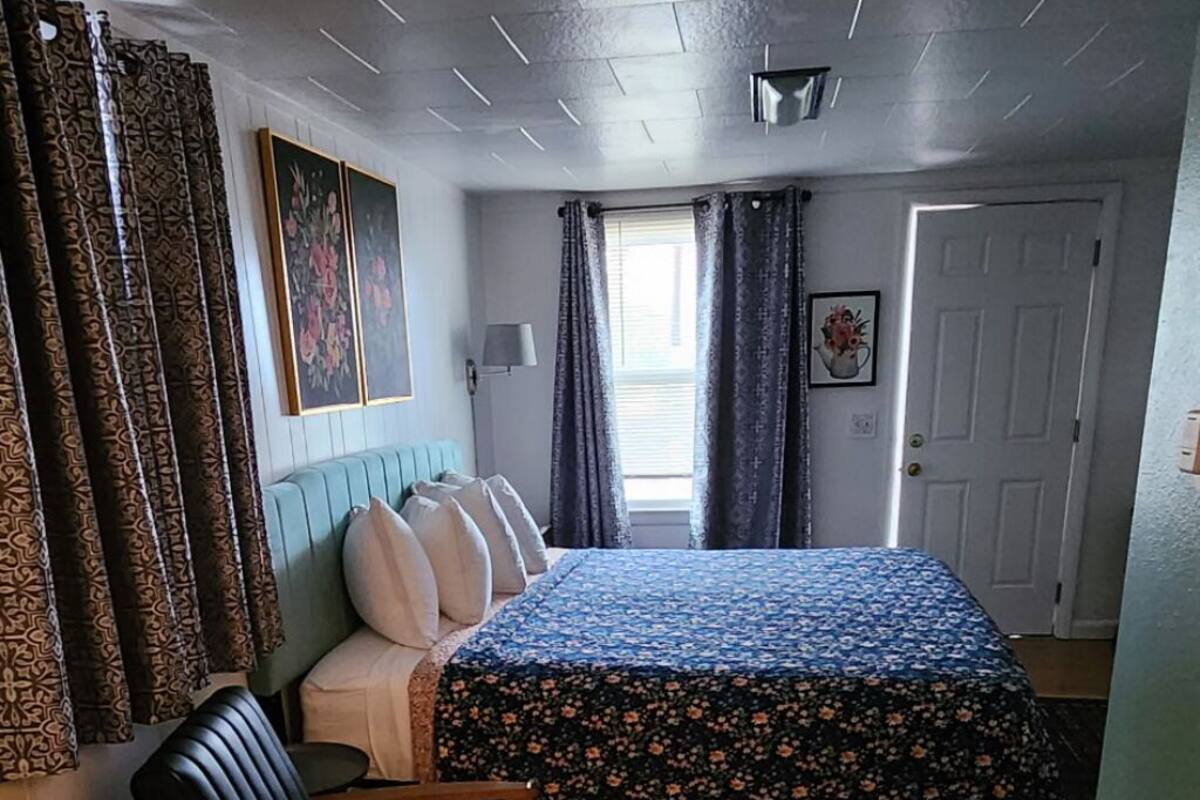Een kamer met een bed, een bureau, een stoel en een kamerbreed tapijt met een patroon.