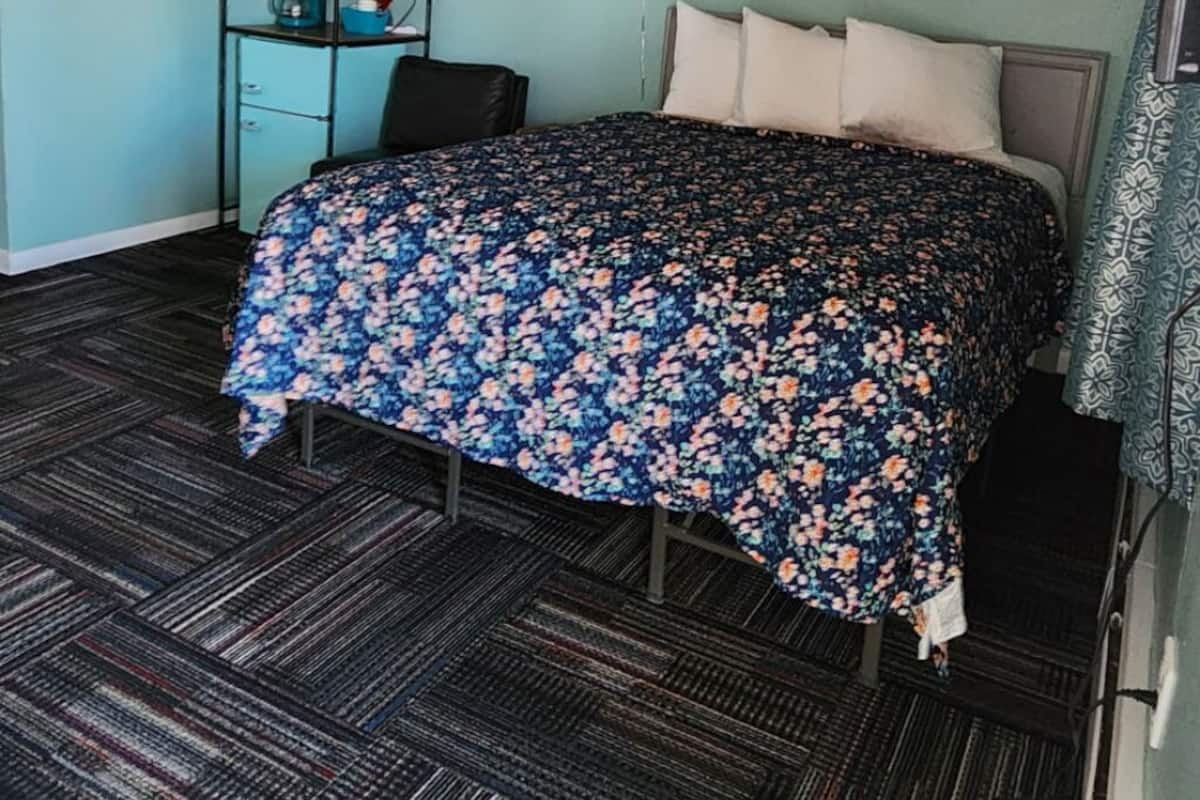 Een kamer met een bed, een bureau, een stoel, een spiegel en een wandplank.