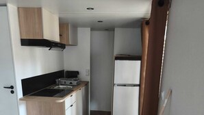 Een kleine keuken met een fornuis, spoelbak en koelkast.