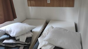 Twee bedden met kussens en een houten plank erboven.