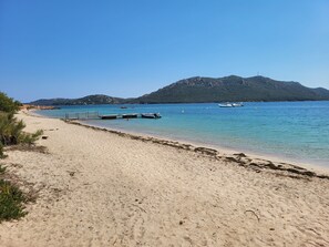 A beach with clear water, a dock, and a mountain in the background. - 2-bedroom mobile home near Porto-Vecchio at the "Les Chênes" campground (Porto-Vecchio)