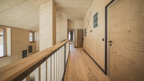 A wooden interior with a long hallway, wooden walls, and a wooden railing. - Luxury Chalet in Bichlbach (Bichlbach)