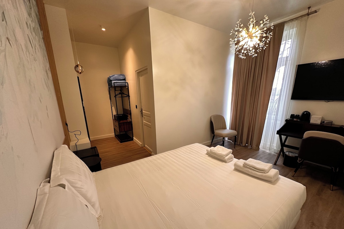Ein Hotelzimmer mit einem Bett, einem Schreibtisch mit Stuhl, einem Fernseher und einem Kleiderschrank.