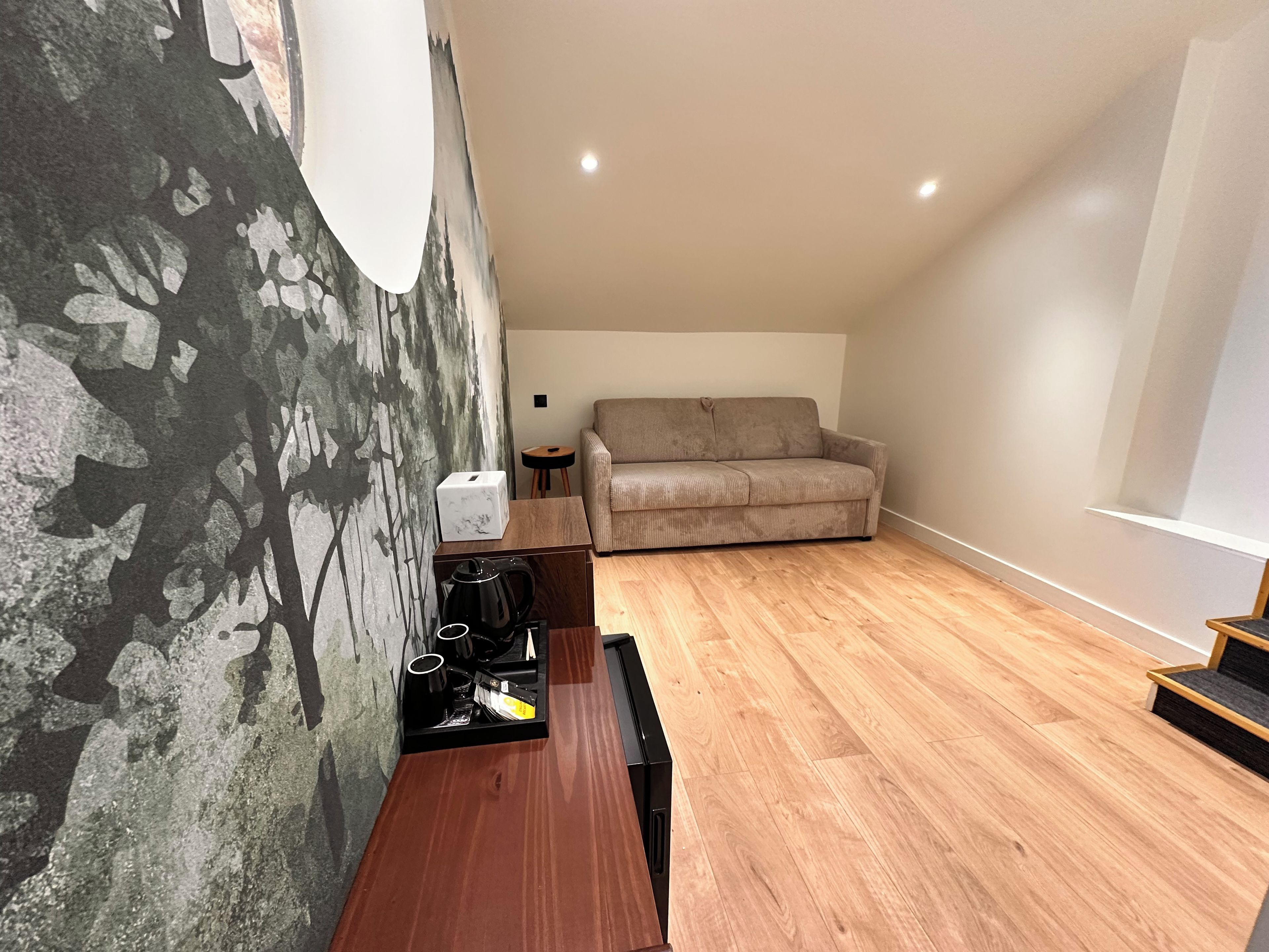 Una sala de estar moderna con un sofá, una mesa de centro y una pared con un mural de un árbol.