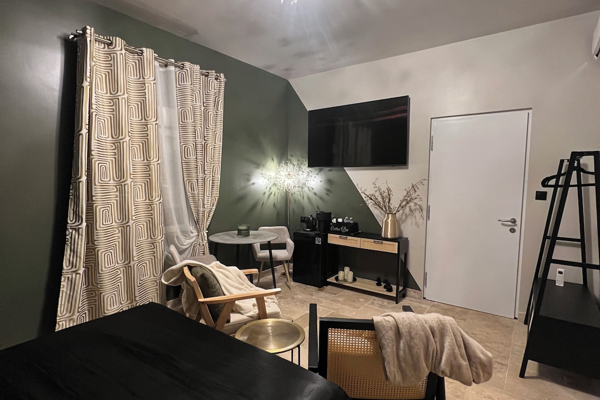 Ein Schlafzimmer mit Bett, Stuhl, Schreibtisch, Fernseher und einer Tür.