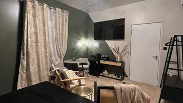 Un dormitorio con cama, una silla, escritorio, televisor y una puerta.