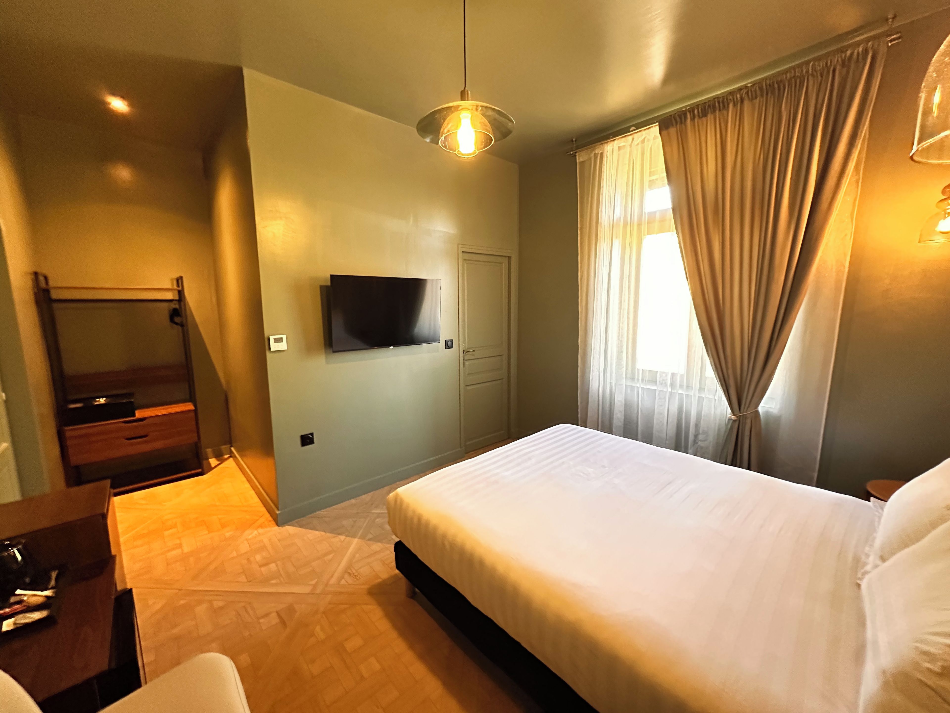 Une chambre d’hôtel équipée d’un lit, d’un téléviseur fixé au mur, d’un bureau et d’une chaise.