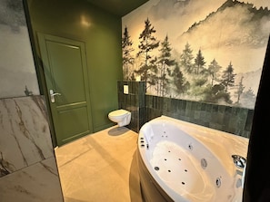 Un baño con piso de mármol, una puerta verde, un inodoro y una bañera grande.