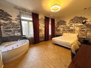 Ein Schlafzimmer mit einem großen Bett, einer Badewanne und einem Esstisch.