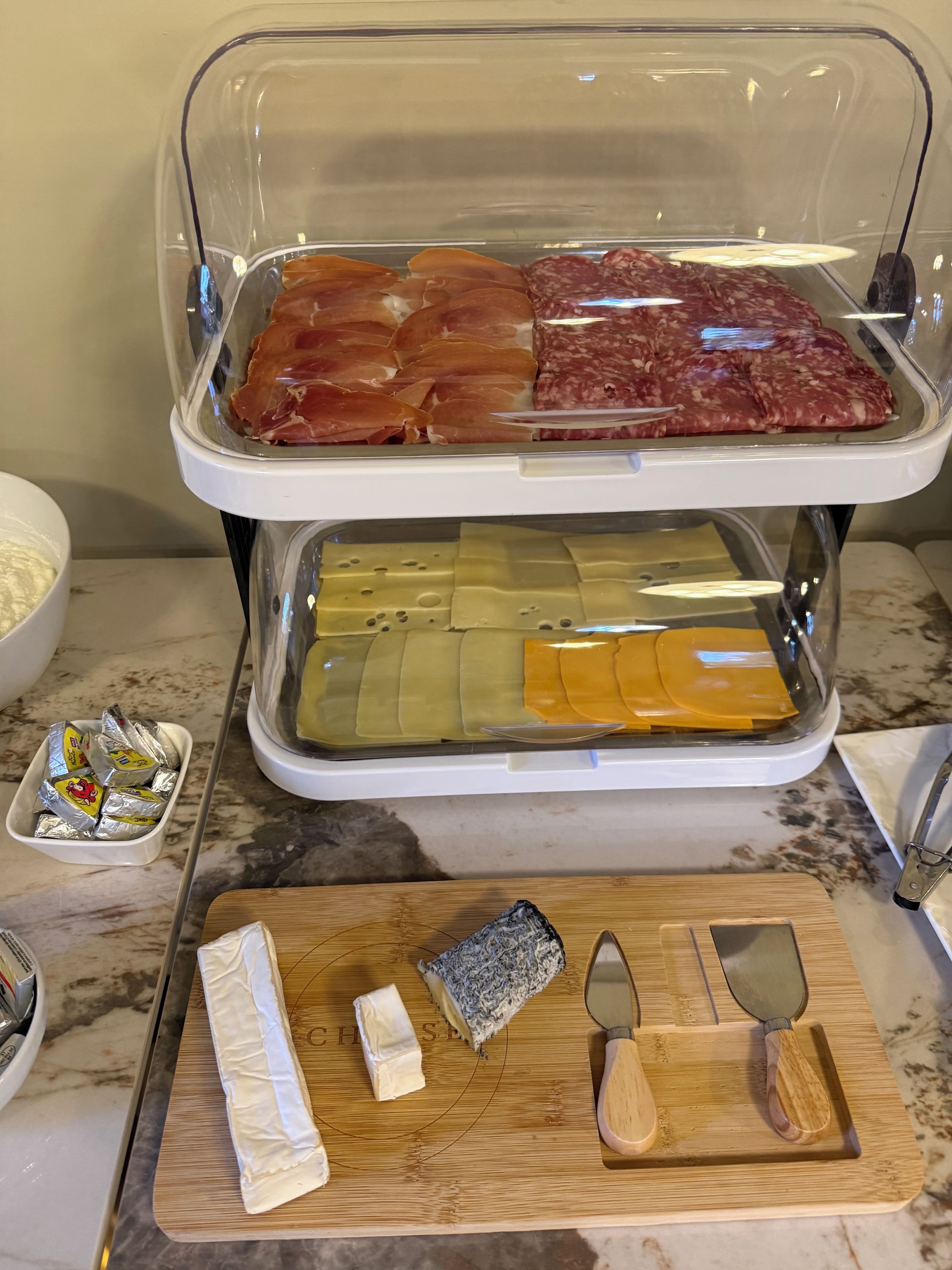 Un plan de travail de cuisine sur lequel on trouve une variété d’aliments, notamment de la viande, du fromage et des condiments.