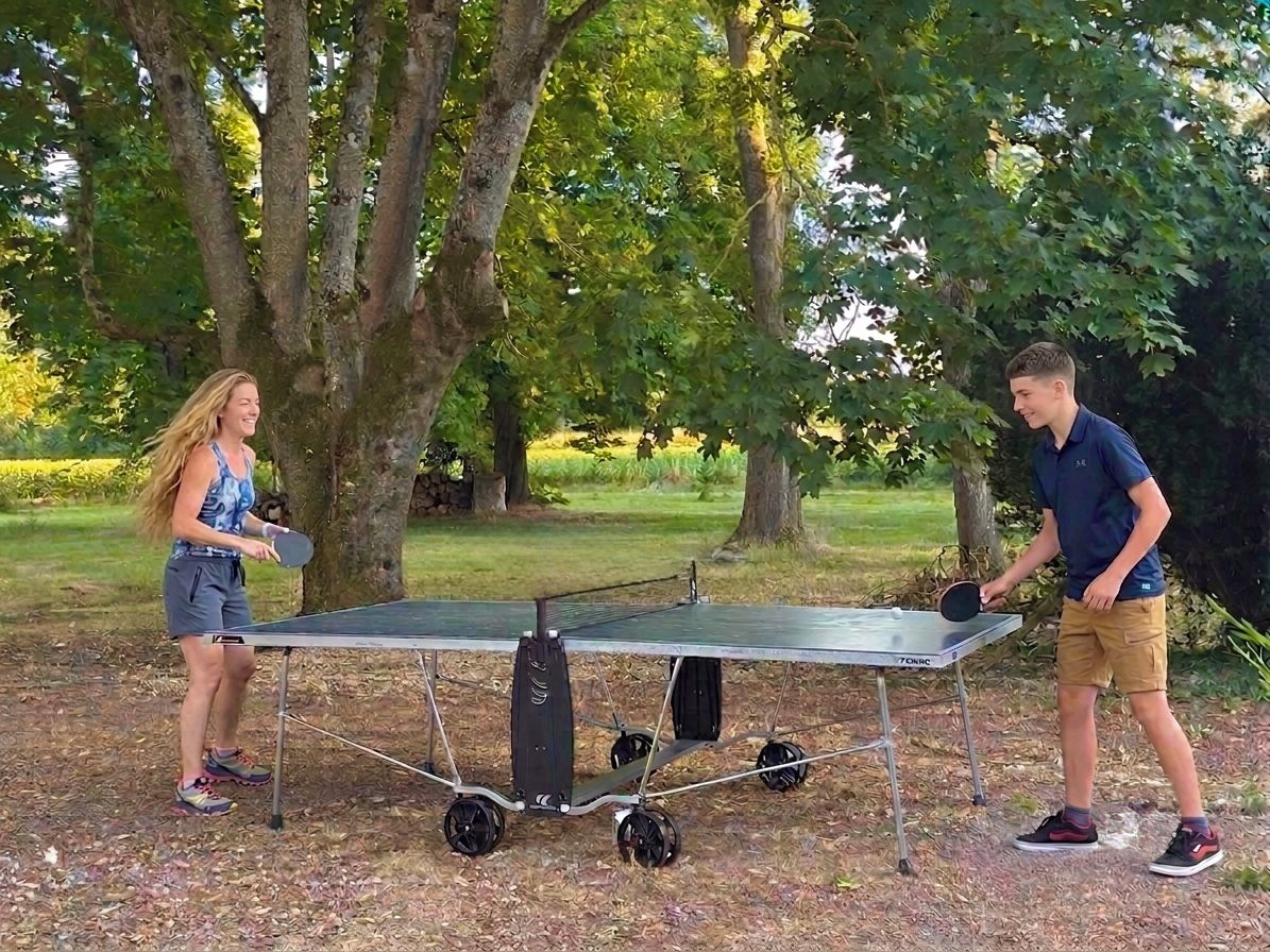 Two people playing table tennis outdoors with a portable table.