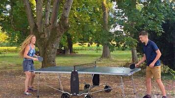 Two people playing table tennis outdoors with a portable table.
