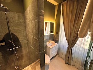 Ein Badezimmer mit Dusche, Toilette, Waschbecken und Spiegel.