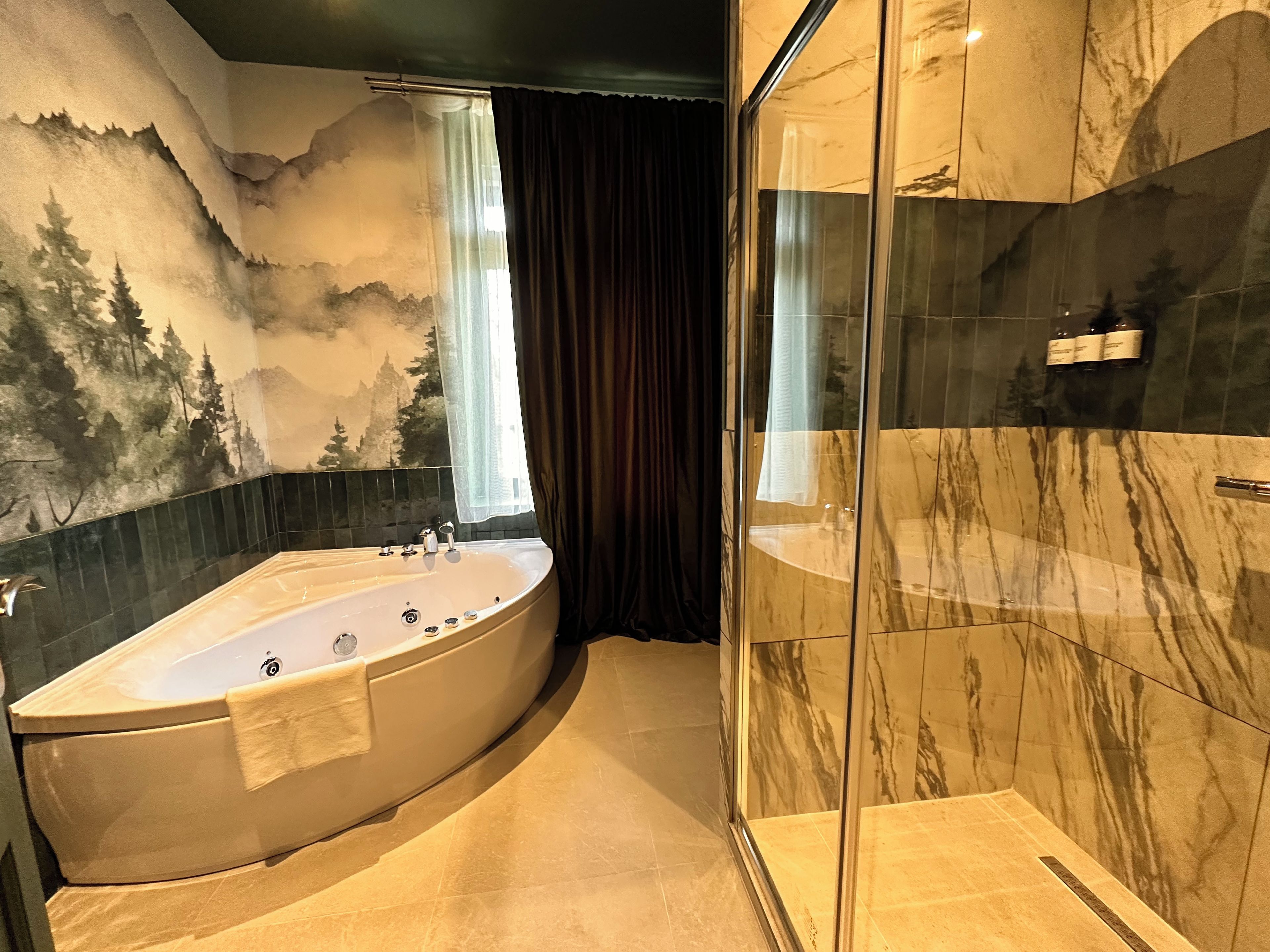 A modern bathroom with a freestanding bathtub, a glass-enclosed shower, and a decorative wall mural.