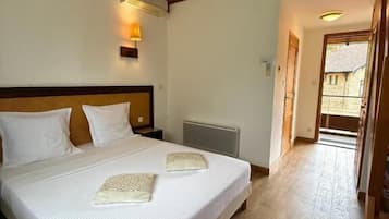 A bedroom with a large bed, a wooden headboard, an air conditioning unit, and a staircase leading to an upper level.