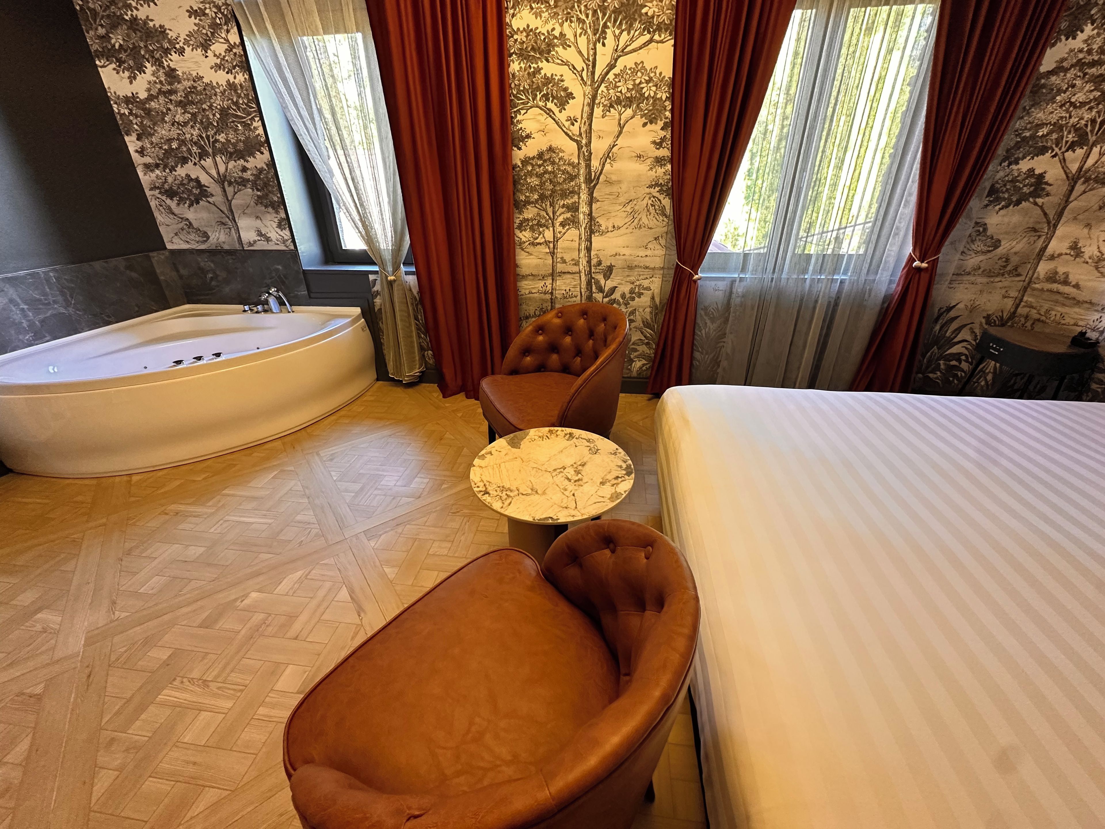 Quarto com uma banheira grande, cama, mesa redonda e poltrona de couro.