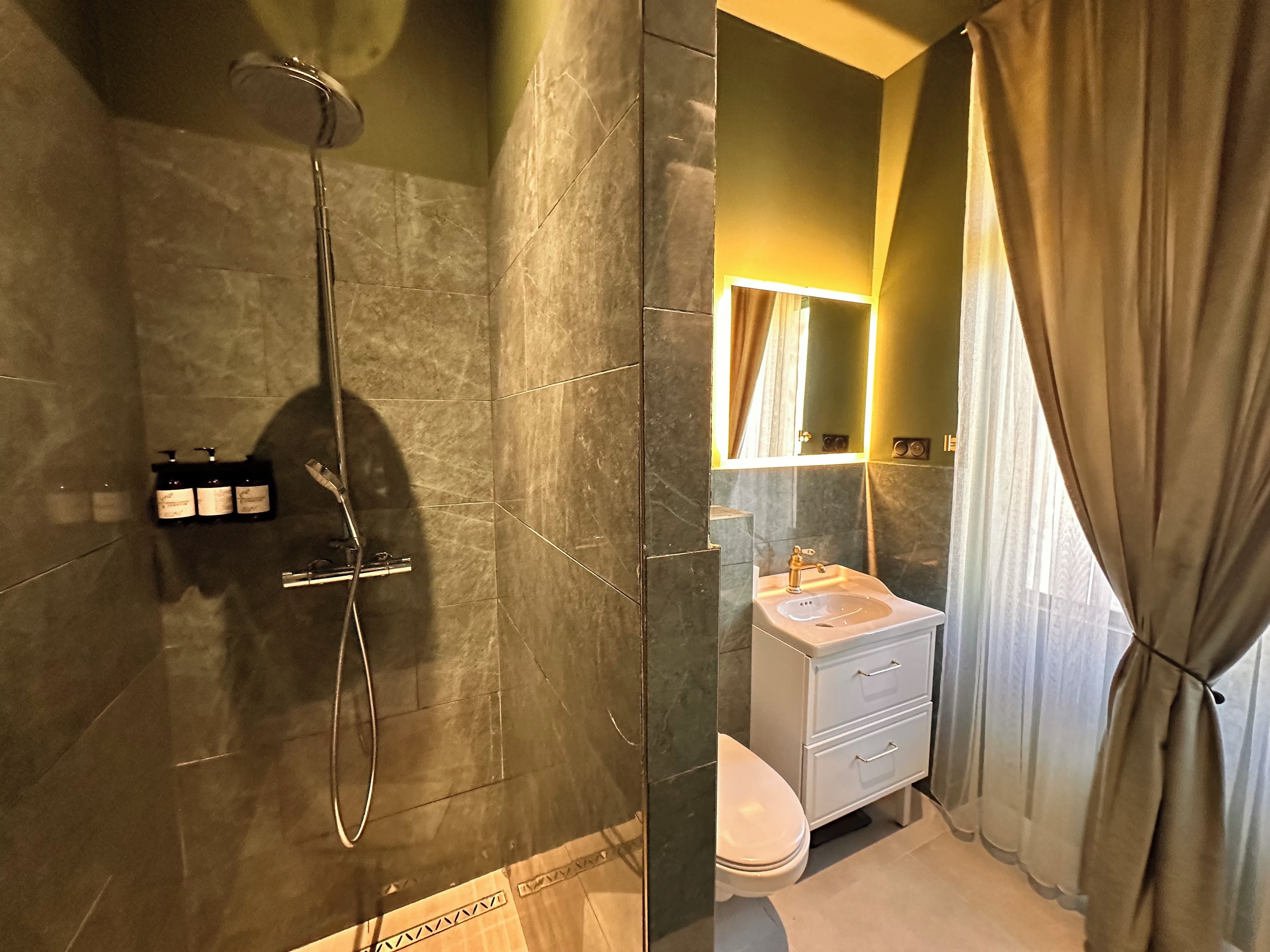 Un baño con ducha, inodoro, lavabo y espejo.