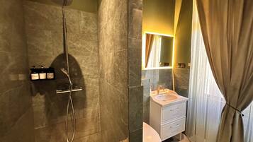 Un baño con ducha, inodoro, lavabo y espejo.