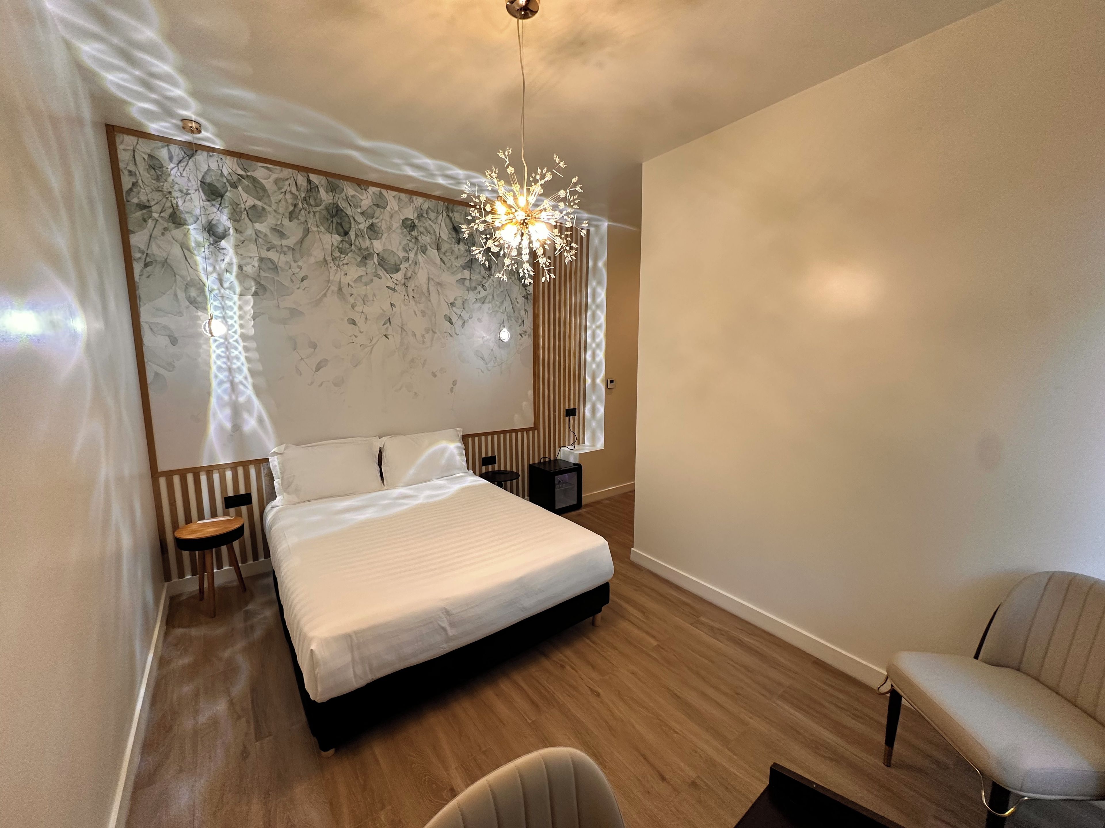 Un dormitorio moderno con una cama grande, un escritorio, una silla y una lámpara decorativa.