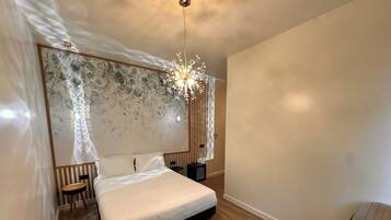 Un dormitorio moderno con una cama grande, un escritorio, una silla y una lámpara decorativa.