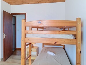 A bunk bed with a wooden frame, a small bedside table with a lamp, and a door leading to another room. - Arceau 3 by Interhome (Ile d'Oléron)