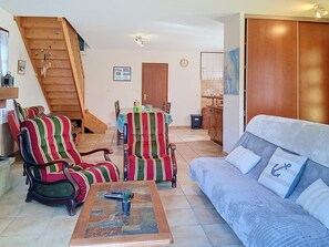 A living room with a sofa, striped armchairs, a coffee table, a staircase, a dining area, and a kitchen. - Arceau 3 by Interhome (Ile d'Oléron)