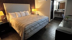 A hotel room with a large bed, bedside tables, a desk, and a mirror. - Maviri Hotel (Tijuana)