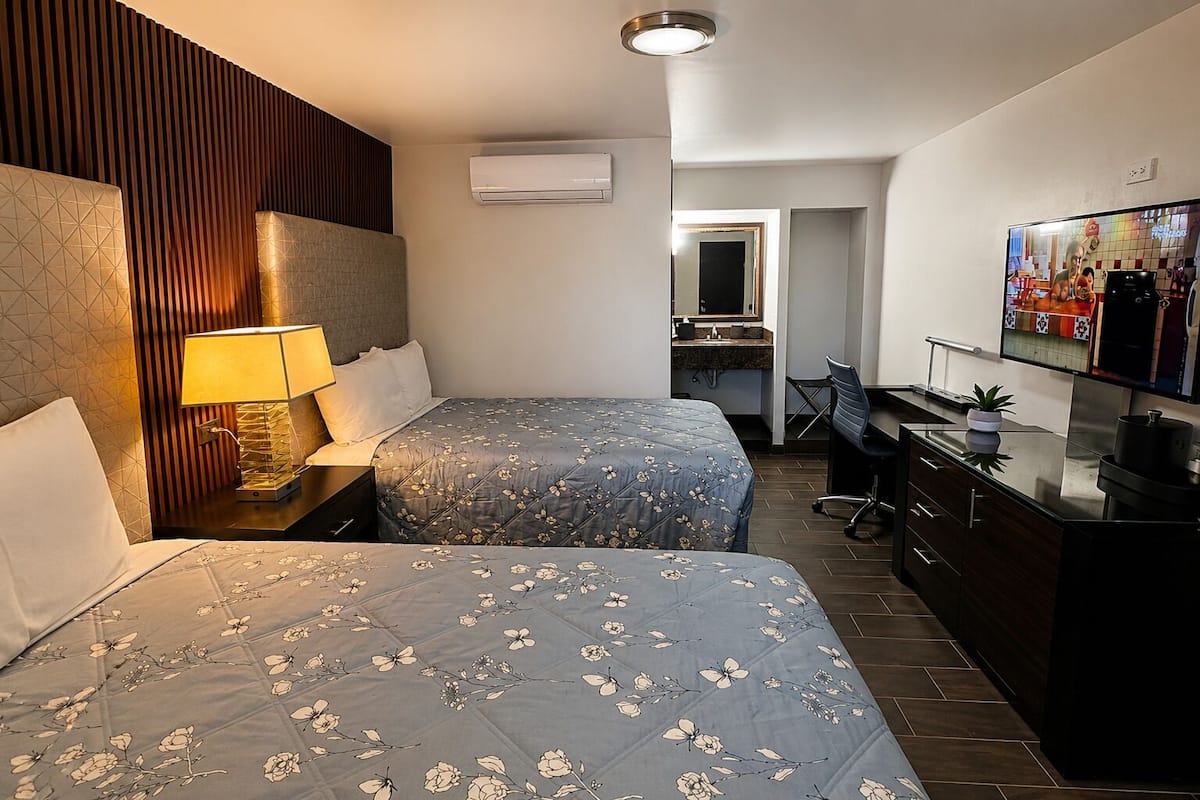 Hotellihuone, jossa on kaksi sänkyä, työpöytä, televisio ja ilmastointilaite.