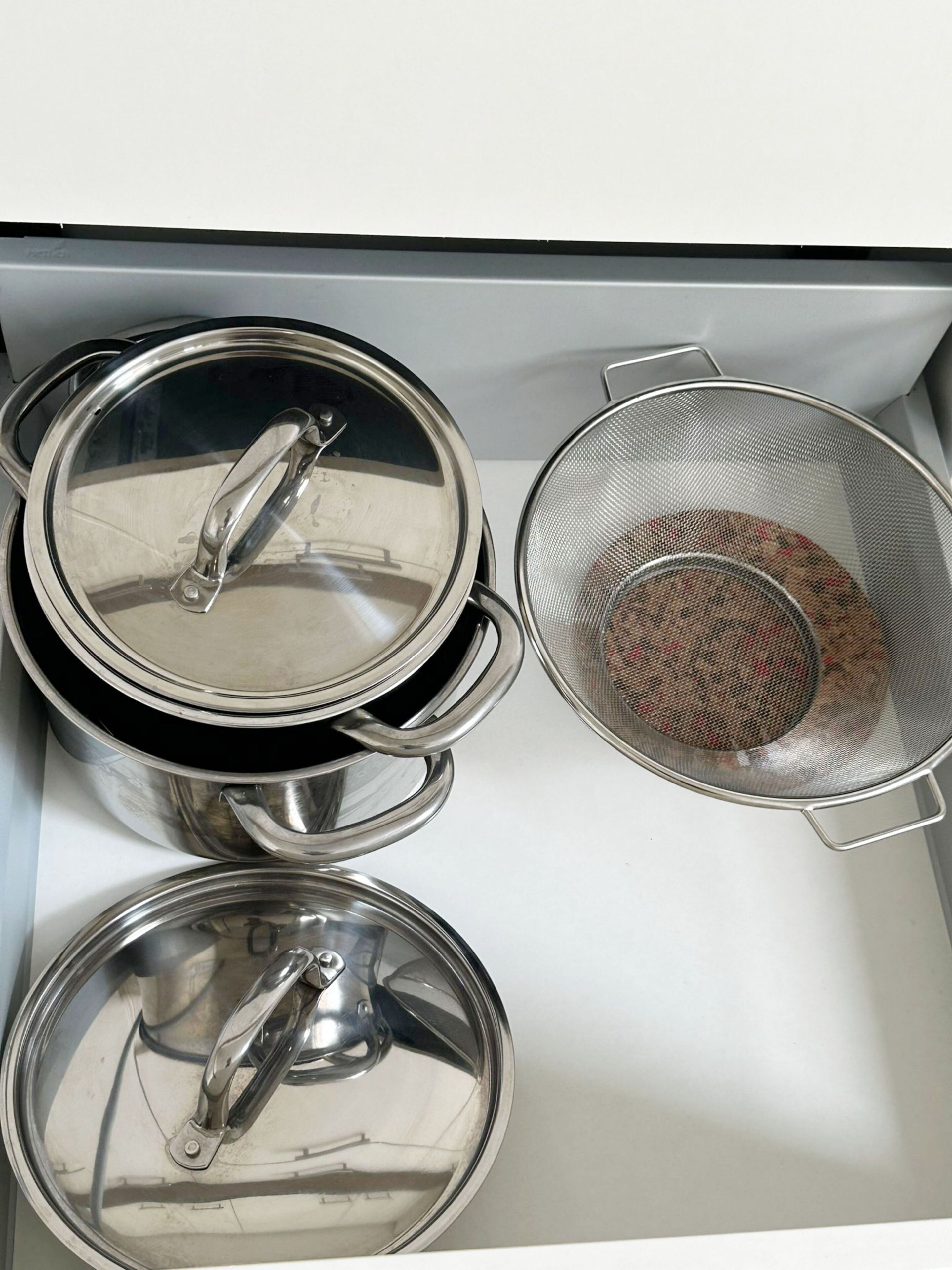 A kitchen with stainless steel pots and a colander.