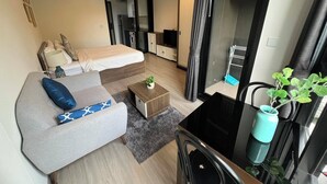 Een moderne hotelkamer met een bed, een bank, een salontafel, een televisie en een kitchenette.