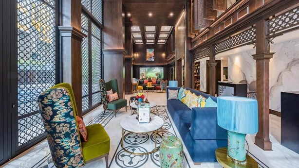 Een ruime lobby met een bank, stoelen, een salontafel en een open haard.