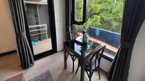 Een klein eetgedeelte met een tafel en stoelen, een raam met uitzicht op groen, en een droogrek.