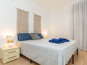A neatly arranged bedroom with a bed, bedside lamps, a nightstand, and a window with curtains. - Matilde by Interhome (St Antoni de Calonge)