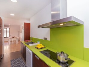 A modern kitchen with a green countertop, a built-in stove, and a stainless steel range hood. - Matilde by Interhome (St Antoni de Calonge)